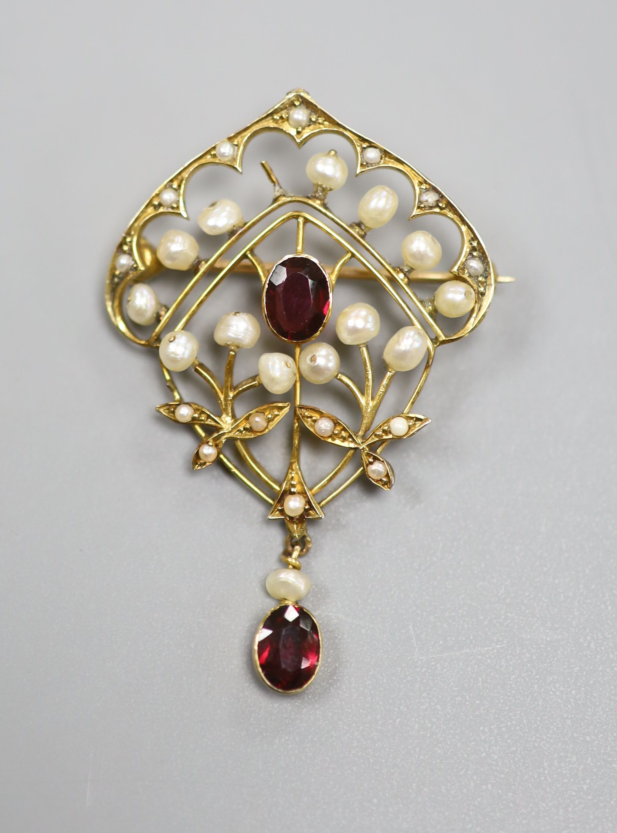 An early 20th century yellow metal, garnet and seed pearl set drop brooch(pearl missing), 47mm, gross 5,2 grams.